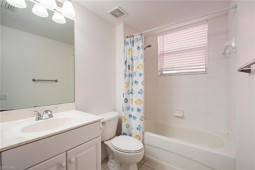 Full bathroom with shower / tub combo with curtain, vanity, toilet, and tile patterned floors