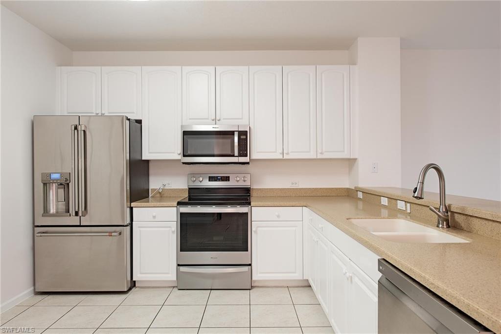 Kitchen with white cabinetry, appliances with stainless steel finishes, sink, and light tile patterned flooring