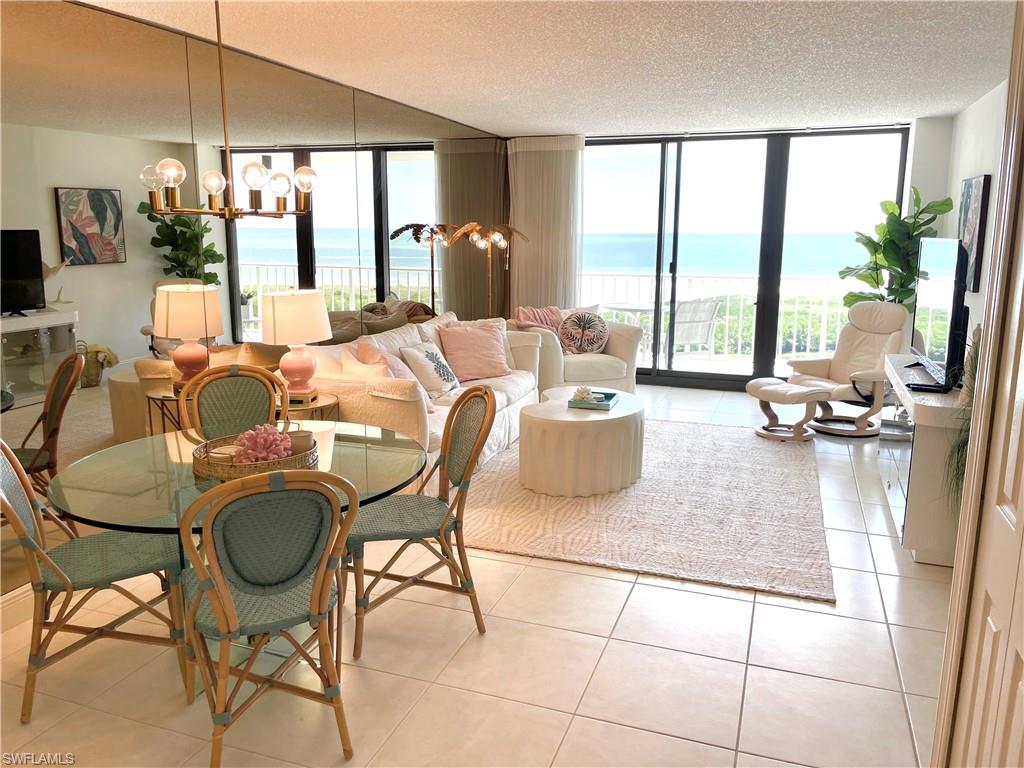 Living room with a chandelier, light tile patterned floors, floor to ceiling windows, plenty of natural light, and a textured ceiling