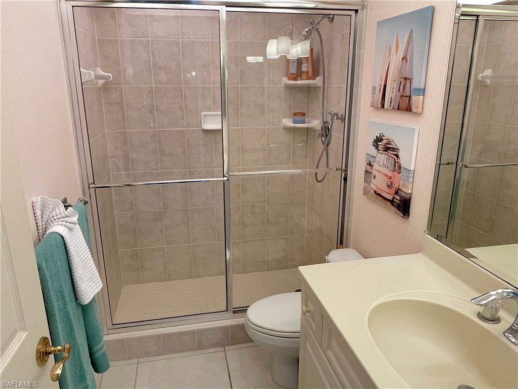 Bathroom featuring tile patterned flooring, vanity, a shower with shower door, and toilet