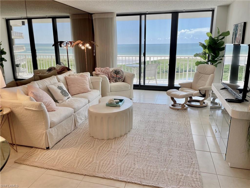 Living room with light tile patterned flooring, plenty of natural light, and floor to ceiling windows