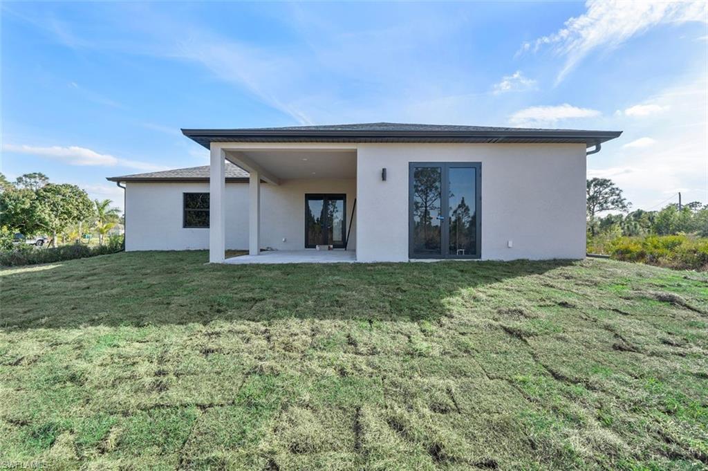 Back of property with stucco siding, a yard, and a patio