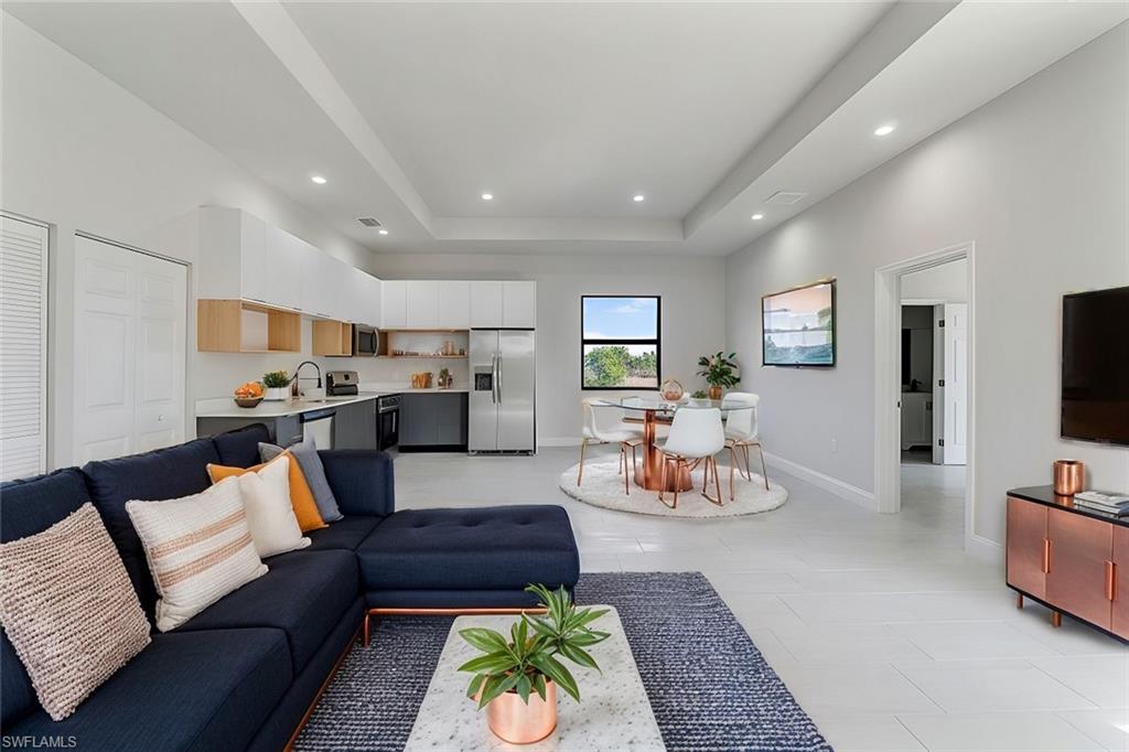 Living area with a tray ceiling, baseboards, and recessed lighting