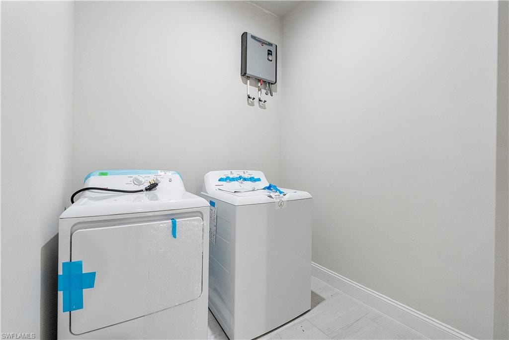 Washroom featuring laundry area, baseboards, and separate washer and dryer