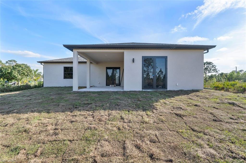 Back of property with a patio area, stucco siding, and a yard