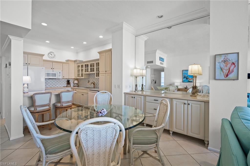 Tiled dining area featuring crown molding, buffet, round glass topped table w/ six chairs