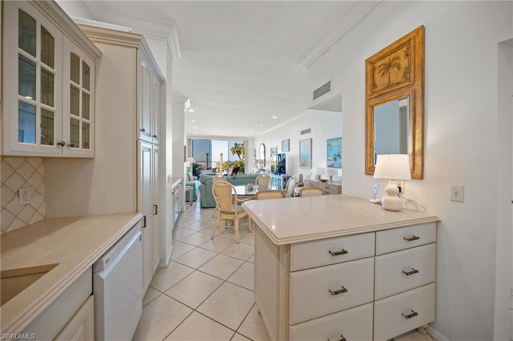 Kitchen featuring neutral pillowed tile patterned floors, dishwasher, ornamental molding, decorative backsplash, and kitchen peninsula