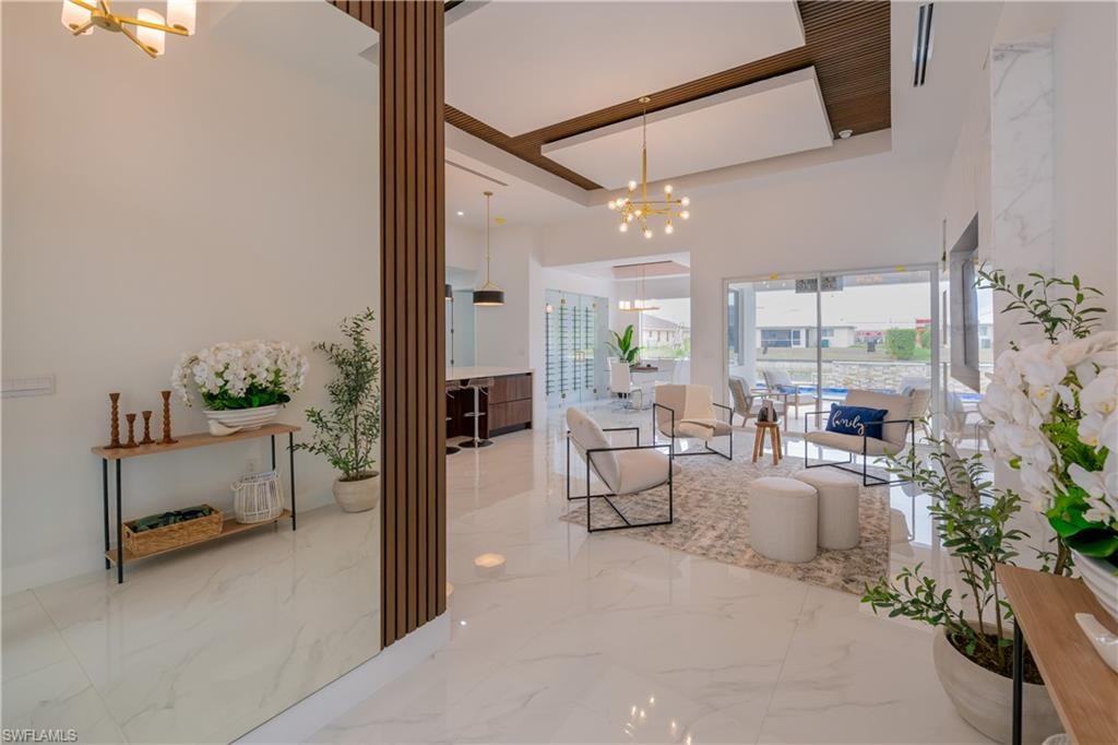 Living room with hanging lights, light marble finish floors, and a high ceiling