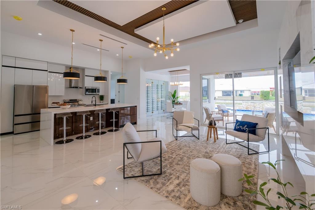 Living room with suspended lighting, a tray ceiling, and light marble finish floors
