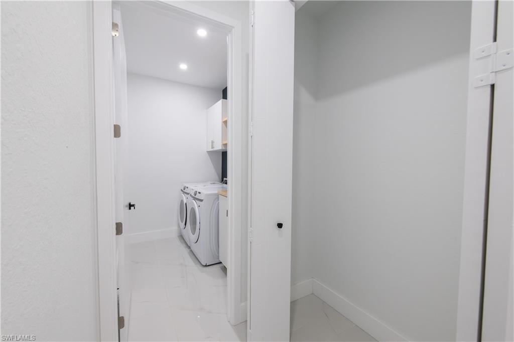 Laundry room with washer and dryer, light marble finish floors, and recessed lighting
