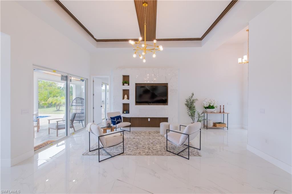 Living area featuring hanging lights, light marble finish flooring, and a high tray ceiling