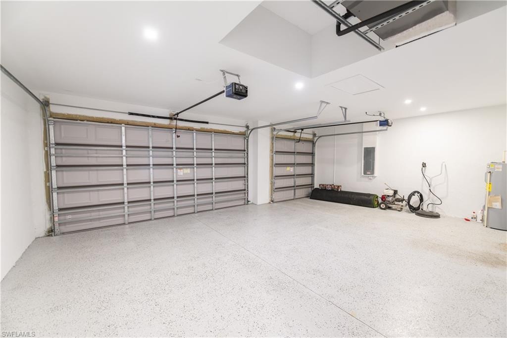 Garage featuring water heater, electric panel, and a garage door opener
