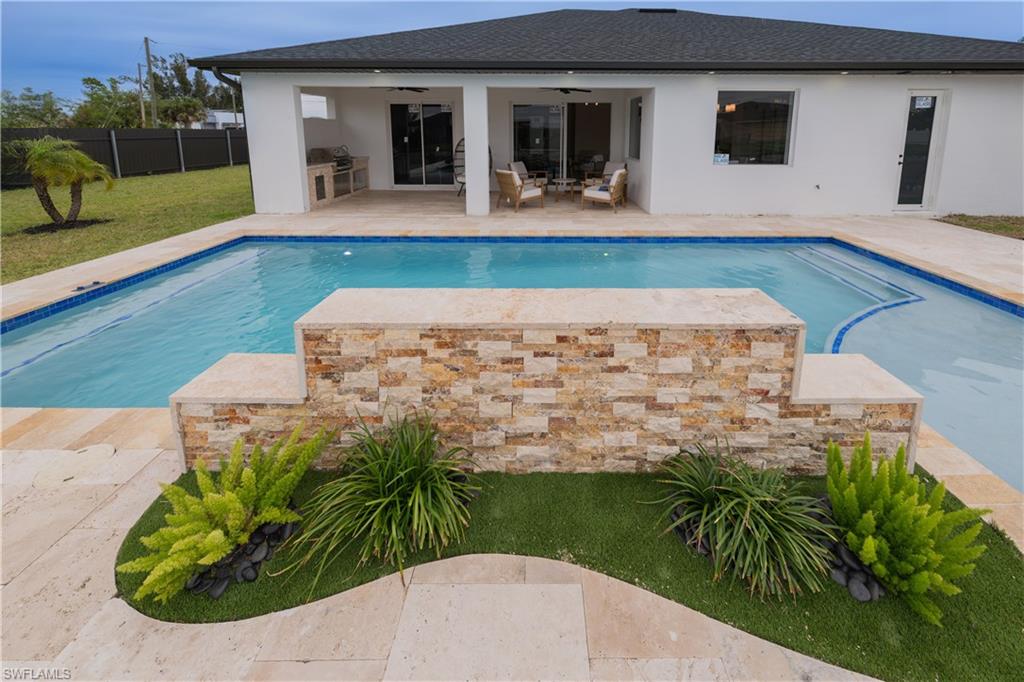 View of swimming pool with patio surround and exterior kitchen
