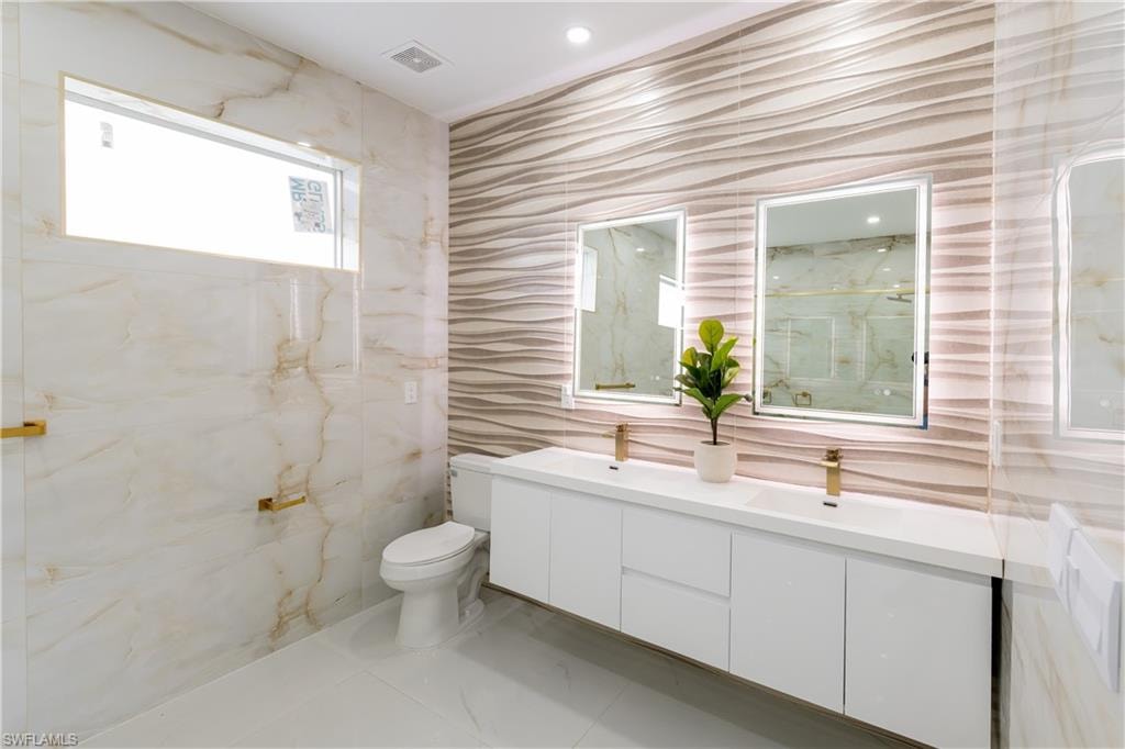 Bathroom with double vanity and tile walls
