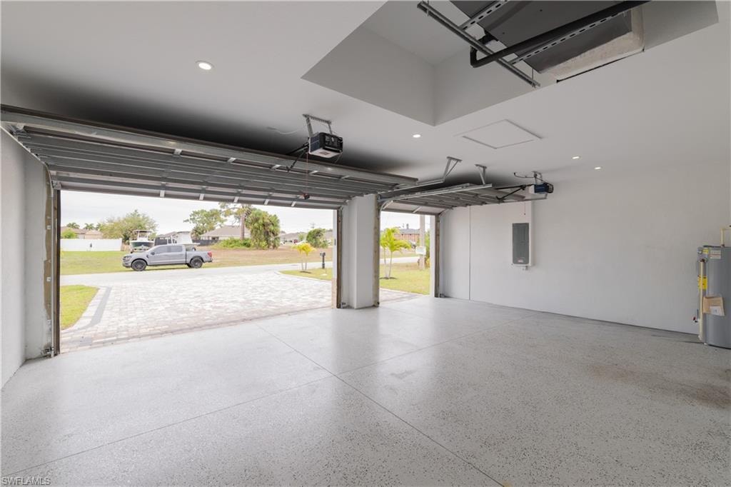 Garage with water heater, recessed lighting, electric panel, and a garage door opener