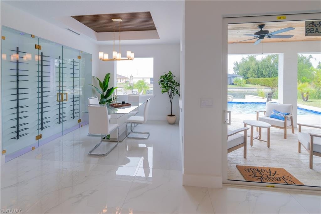Dining space with a raised ceiling, a chandelier, and ceiling fan