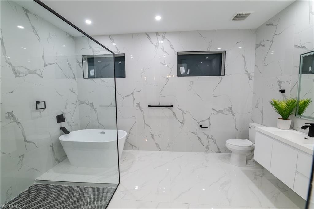 Bathroom with vanity, a washtub, and toilet