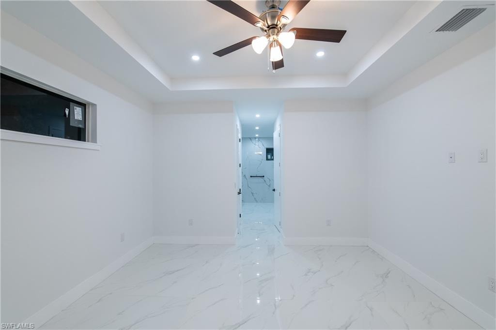 Spare room featuring a raised ceiling and ceiling fan