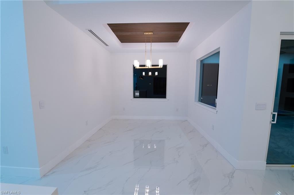 Unfurnished dining area featuring a notable chandelier and a raised ceiling