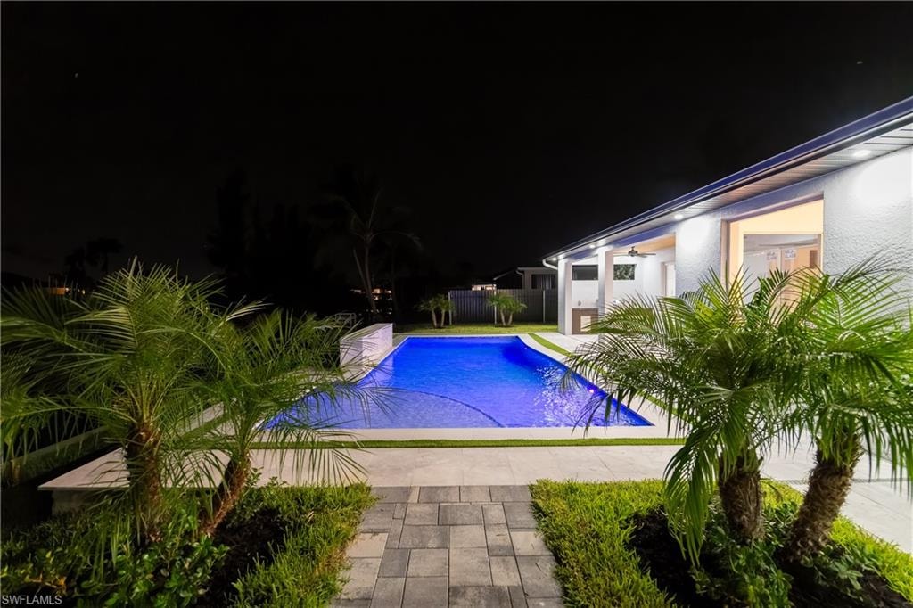 Pool at night with a patio area
