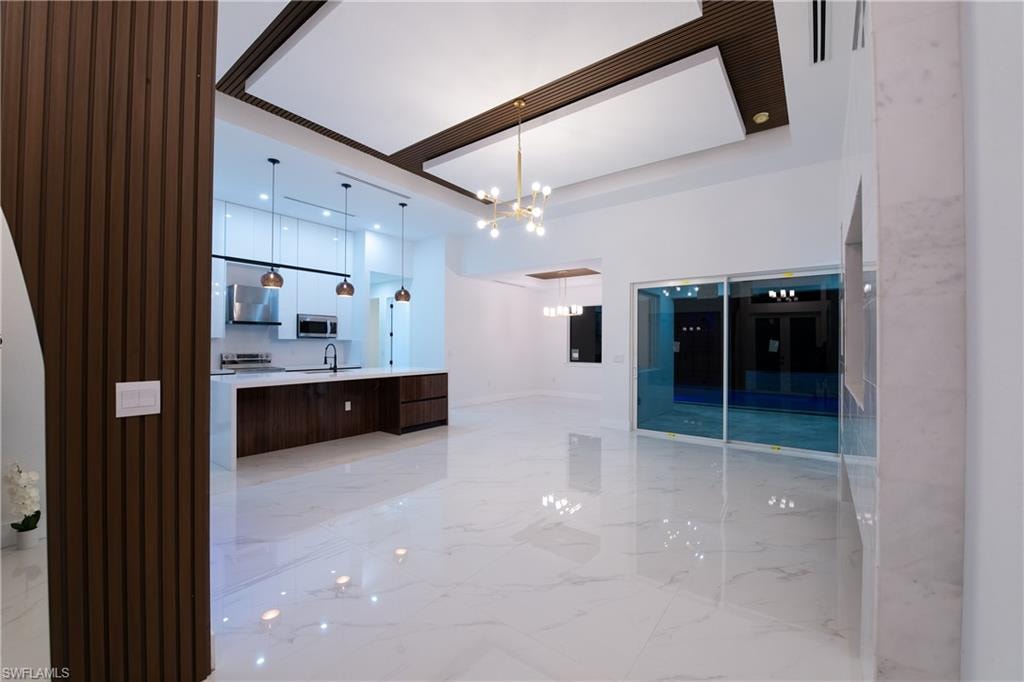 Bathroom with an inviting chandelier, vanity, and a raised ceiling