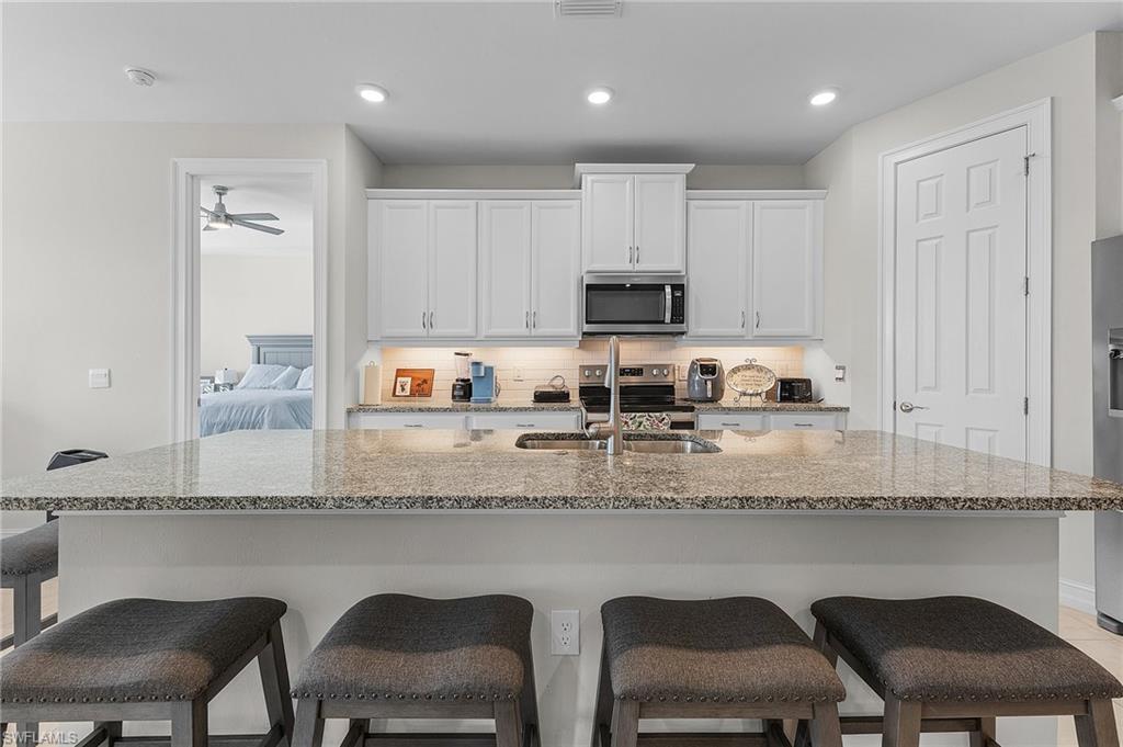 Kitchen featuring white cabinetry, appliances with stainless steel finishes, sink, and a kitchen island with sink