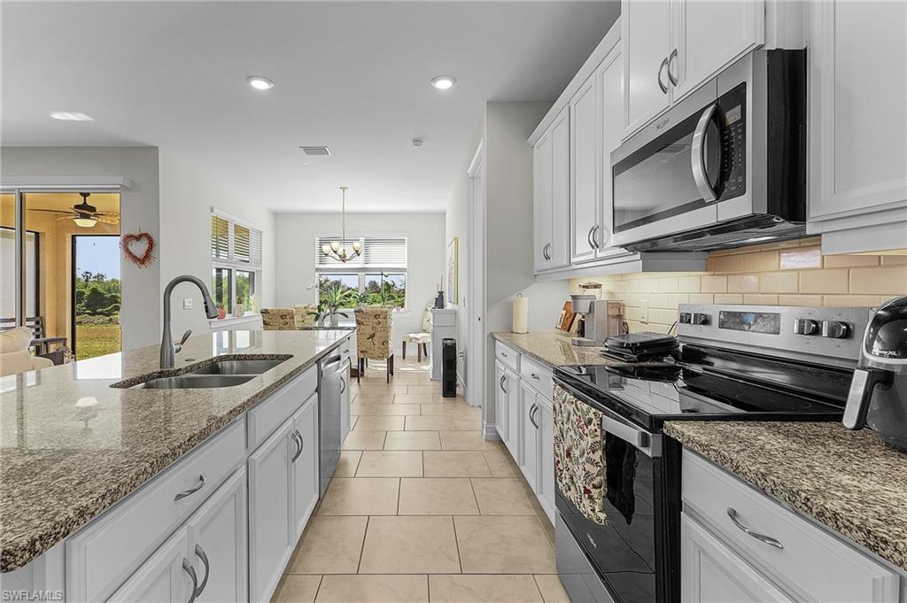 Kitchen featuring appliances with stainless steel finishes, sink, white cabinets, and backsplash