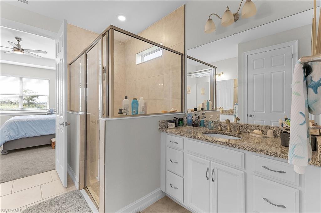 Bathroom featuring an enclosed shower, vanity, tile patterned floors, and ceiling fan