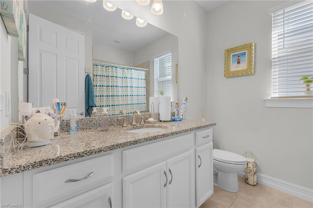 Bathroom featuring walk in shower, vanity, tile patterned floors, and toilet