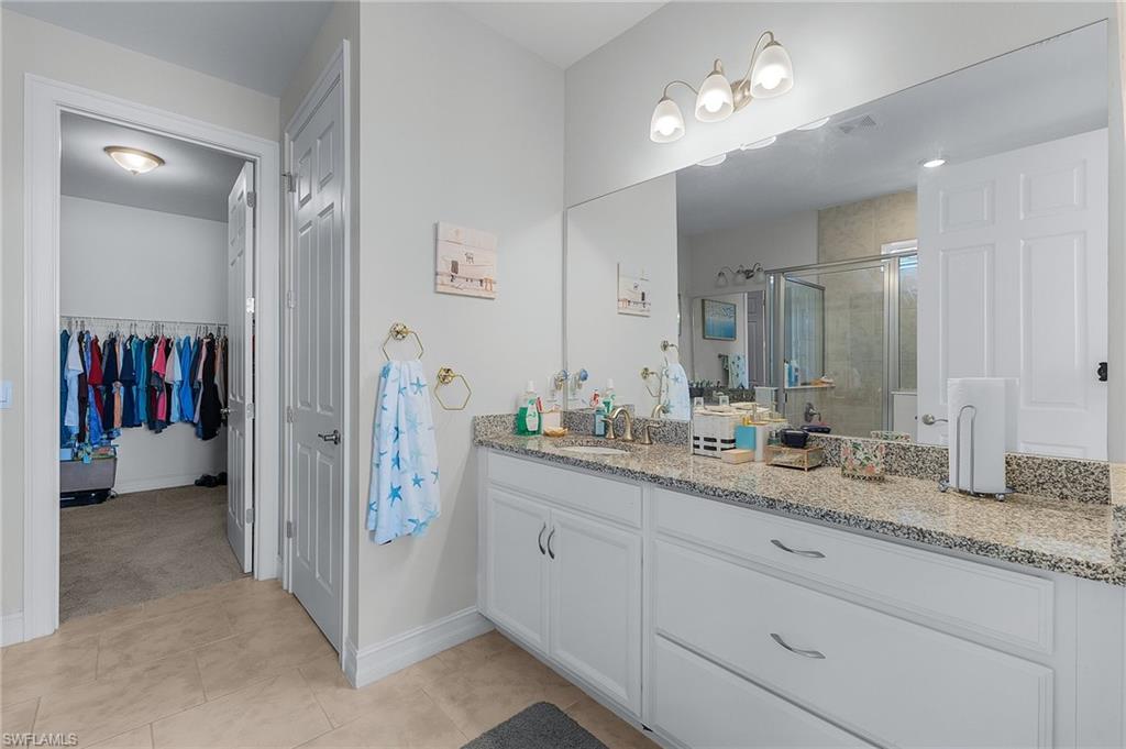 Bathroom featuring vanity, a shower with shower door, and tile patterned flooring