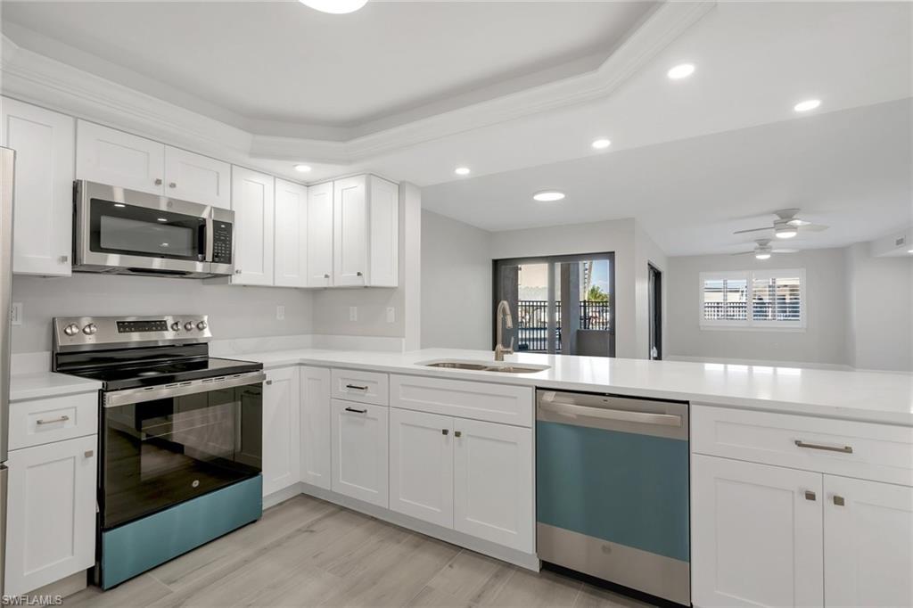 Kitchen featuring appliances with stainless steel finishes, white cabinetry, sink, kitchen peninsula