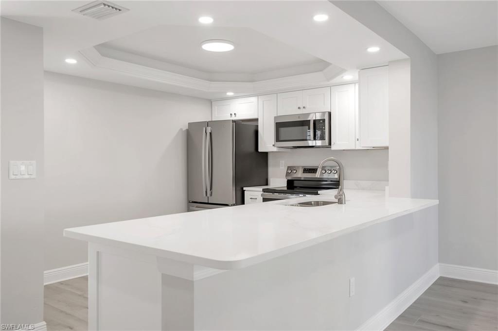 Kitchen with white cabinetry, a tray ceiling, and kitchen peninsula large enough for 4 stools