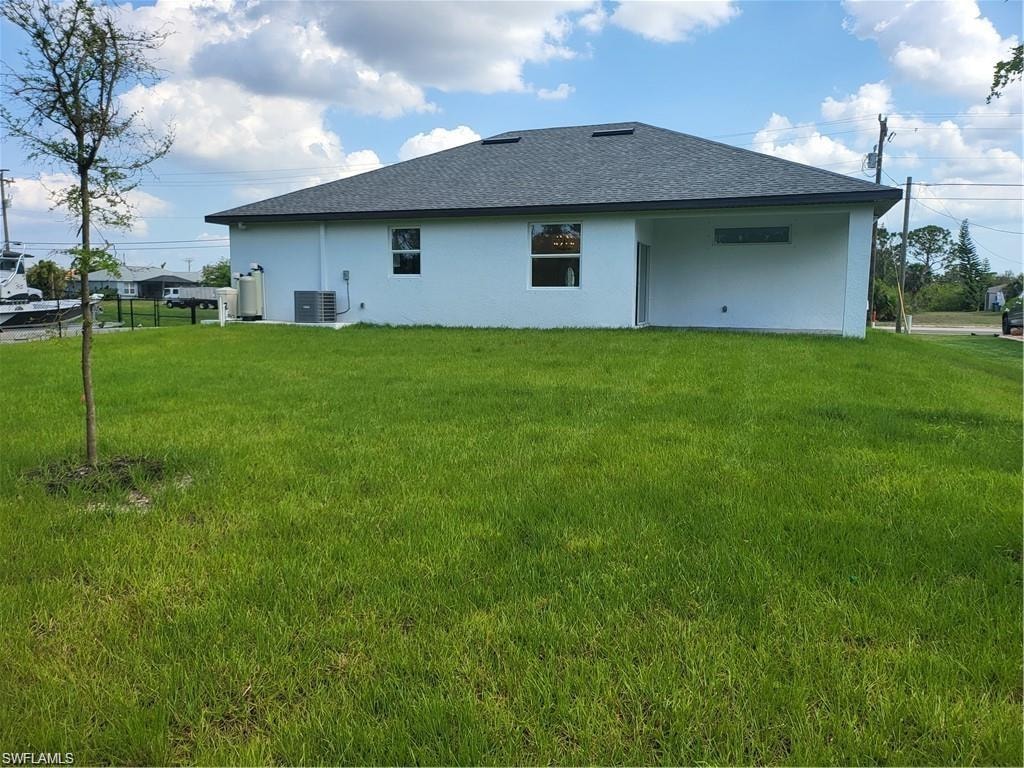 Back of house featuring a yard and central air condition unit