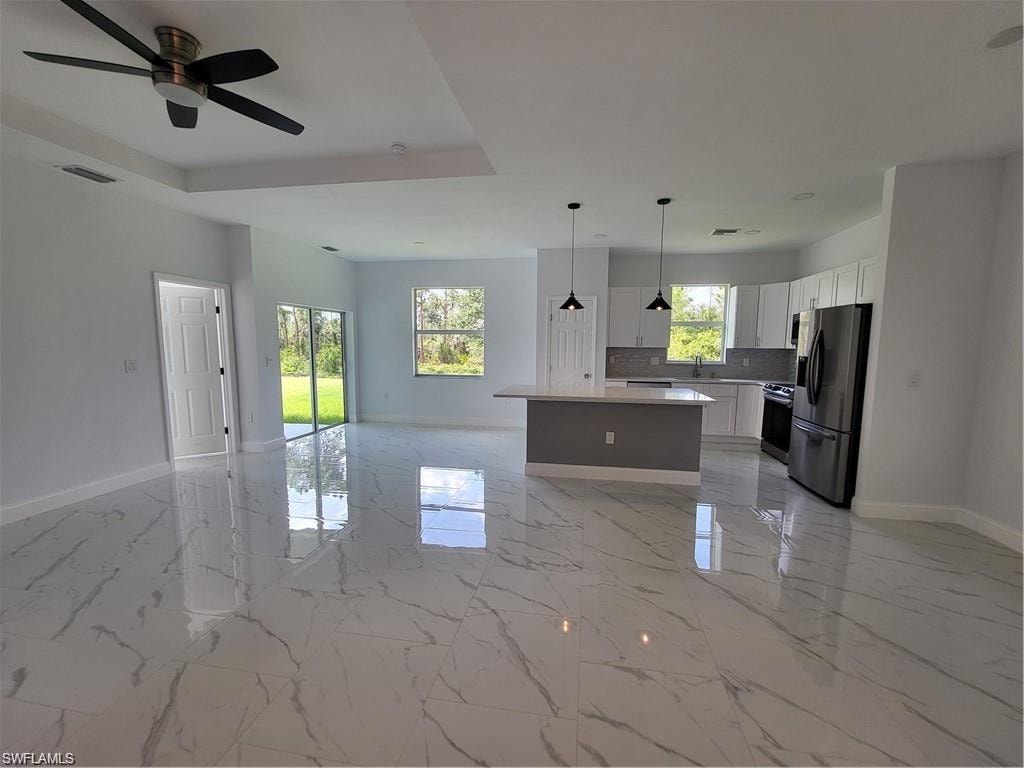Kitchen with white cabinetry, a healthy amount of sunlight, appliances with stainless steel finishes, and a kitchen island
