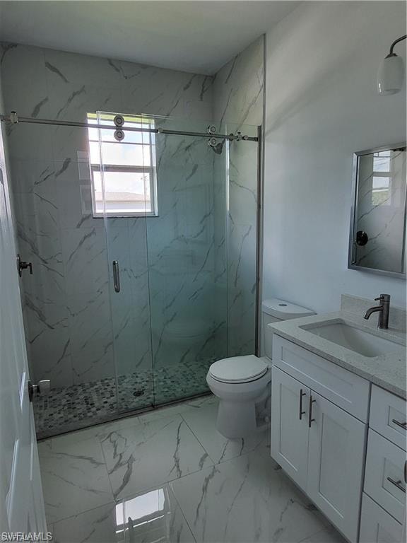 Bathroom with vanity, a shower with door, and toilet