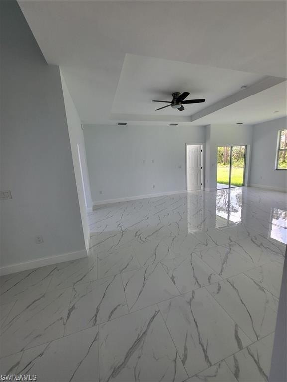 Unfurnished room with ceiling fan and a tray ceiling