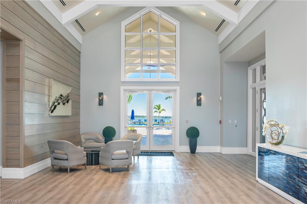 Living area with french doors, wood walls, high vaulted ceiling, light hardwood / wood-style flooring, and beamed ceiling