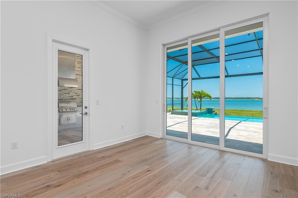 Unfurnished room featuring a water view, crown molding, and light wood-type flooring