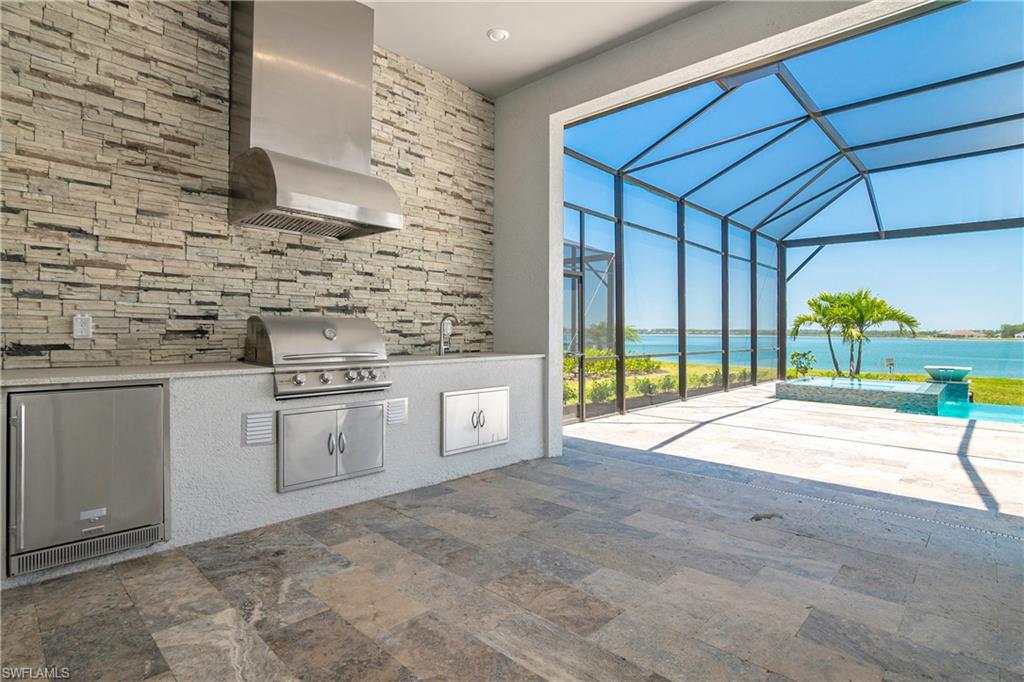 View of patio with a water view, an outdoor kitchen, grilling area, and a lanai
