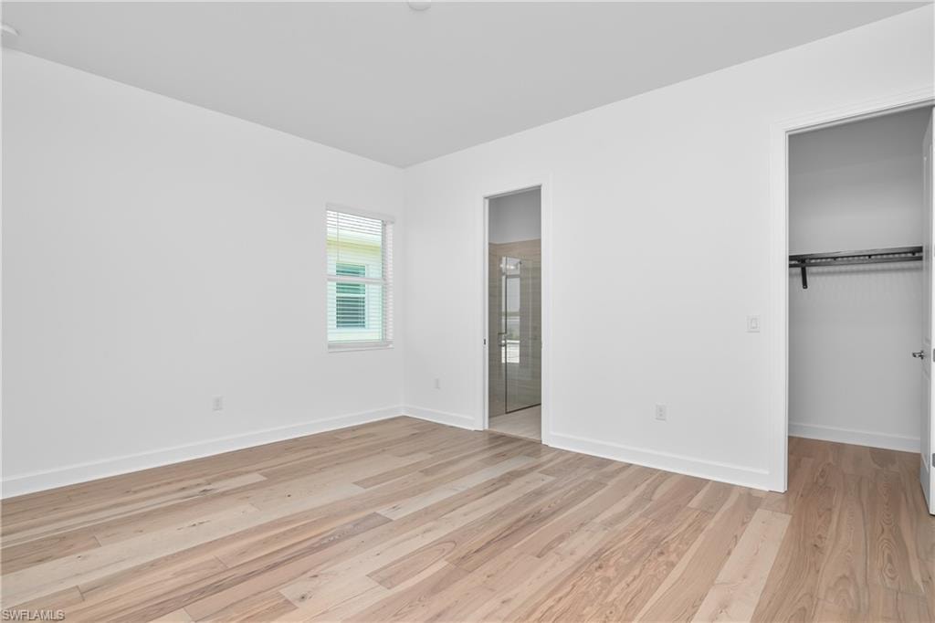 Unfurnished bedroom featuring a walk in closet, light hardwood / wood-style floors, and a closet