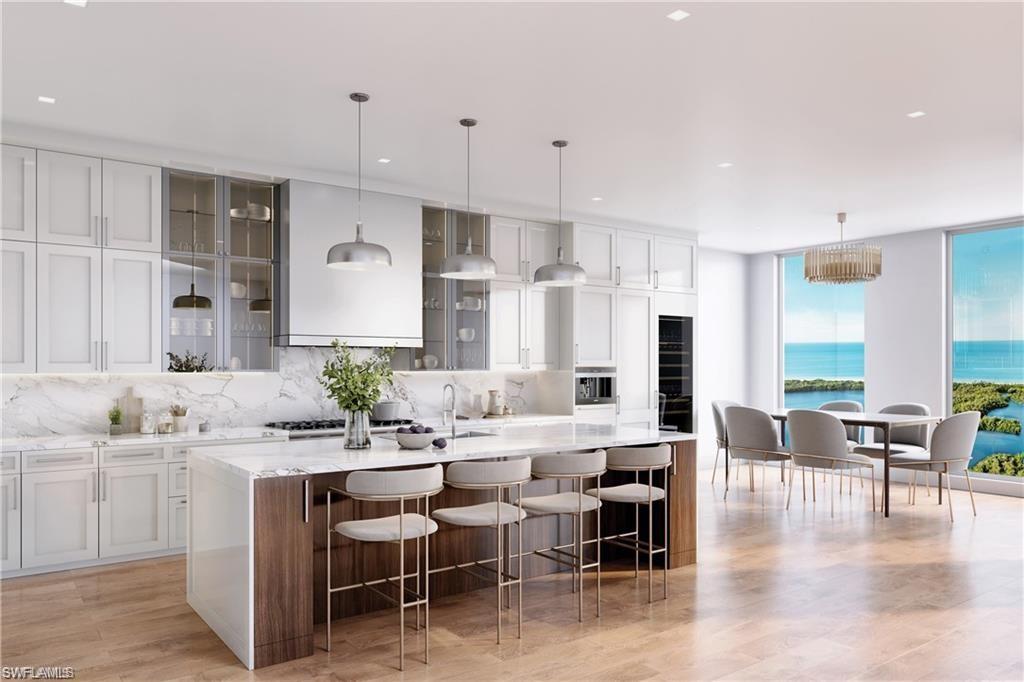 Kitchen with hanging light fixtures, an island with sink, and a kitchen bar