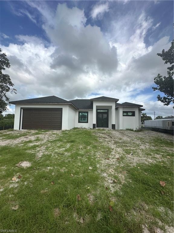Prairie-style home with stucco siding, a garage, and driveway