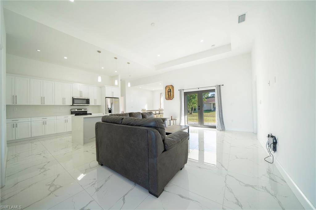 Living room featuring a raised ceiling, a high ceiling, and french doors
