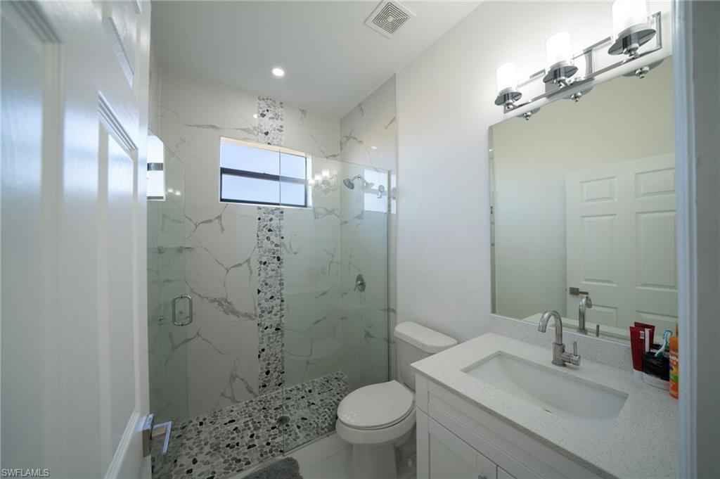 Bathroom with vanity, an enclosed shower, and toilet