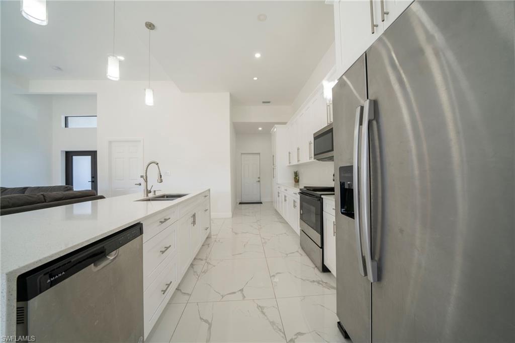 Kitchen featuring white cabinetry, sink, pendant lighting, and stainless steel appliances
