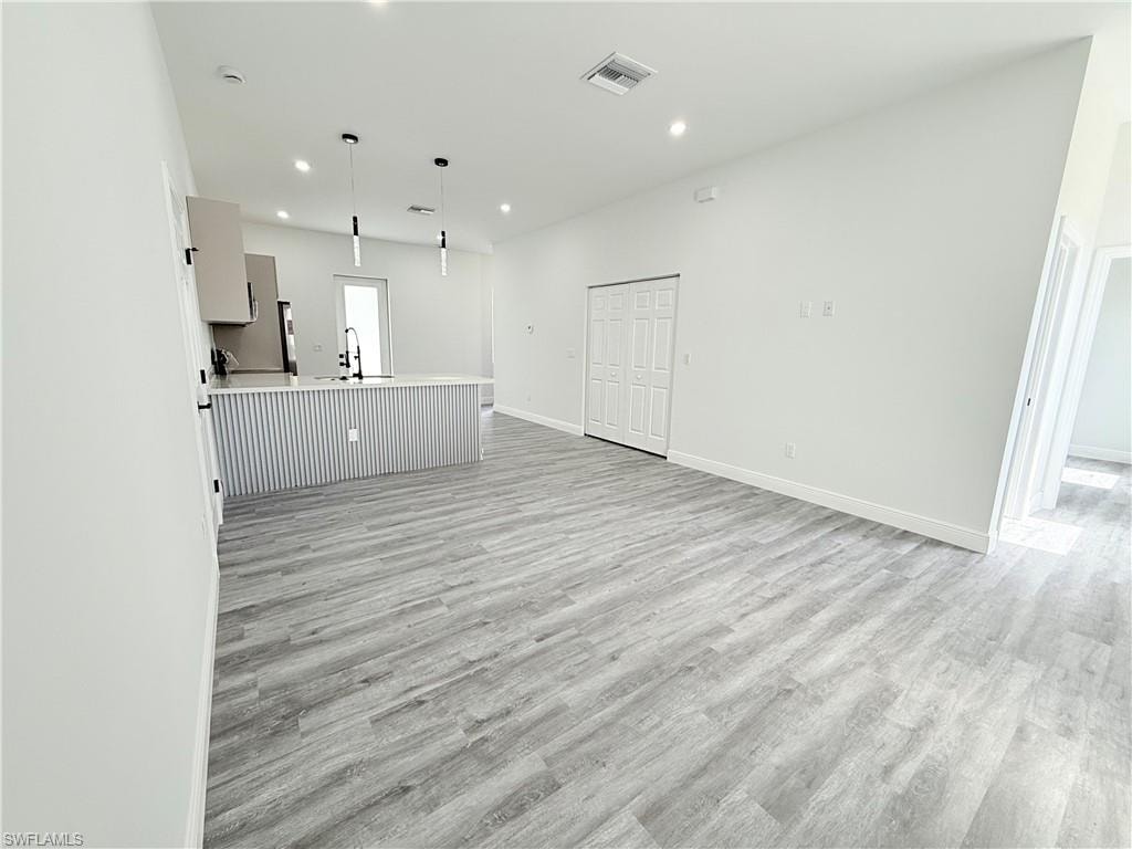 Unfurnished living room with sink and light hardwood / wood-style flooring