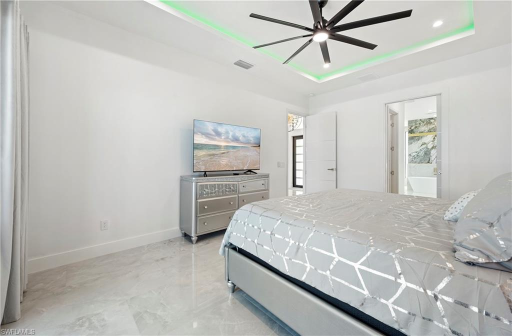 Bedroom featuring a ceiling fan, visible vents, baseboards, a tray ceiling, and recessed lighting