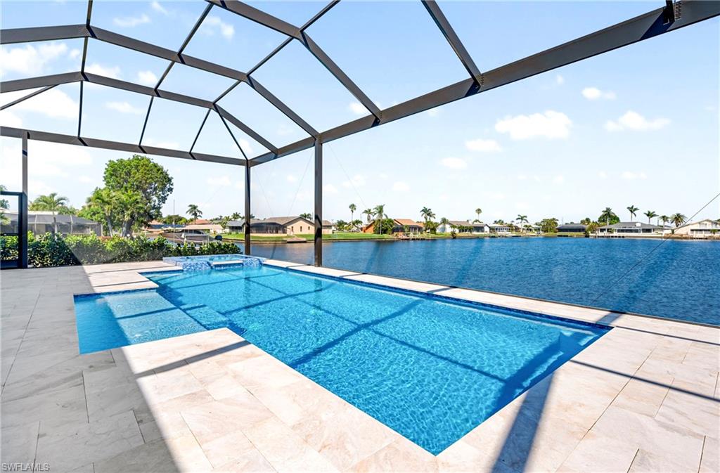 View of swimming pool featuring a patio, a water view, a pool with connected hot tub, and a lanai