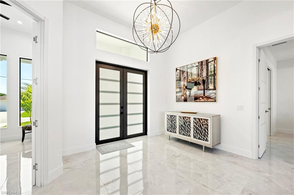 Entrance foyer featuring visible vents, marble finish floor, baseboards, and an inviting chandelier