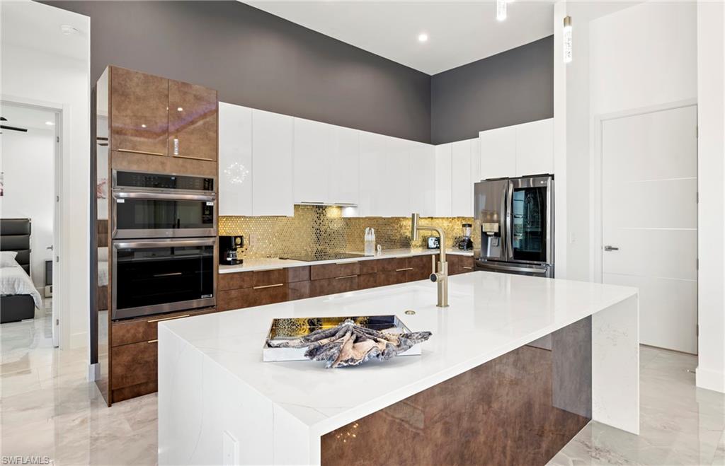 Kitchen with white cabinets, modern cabinets, marble finish floor, and appliances with stainless steel finishes